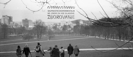 A group of people are walking through a park with buildings and trees in the background.