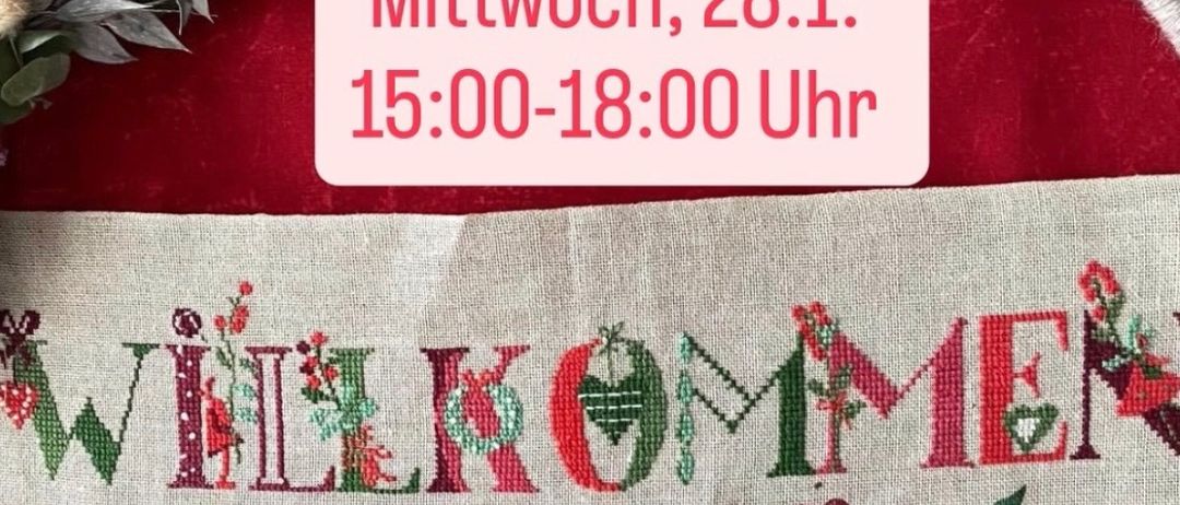 Ein Stoffstück mit den gestickten Worten 'Willkommen' und 'Handarbeitstreff'. Eine Veranstaltungsankündigung auf rotem Tuch zeigt 'Mittwoch, 28.1. 15:00-18:00 Uhr'. Grüne Blätter und rote Blumen schmücken den Stoff.