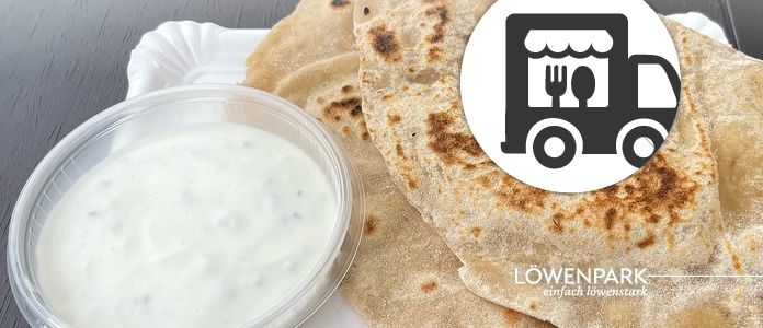 Ein Teller mit zwei Fladenbroten und einer Schüssel mit cremiger Dip, mit einem Logo eines Food Trucks im Hintergrund.