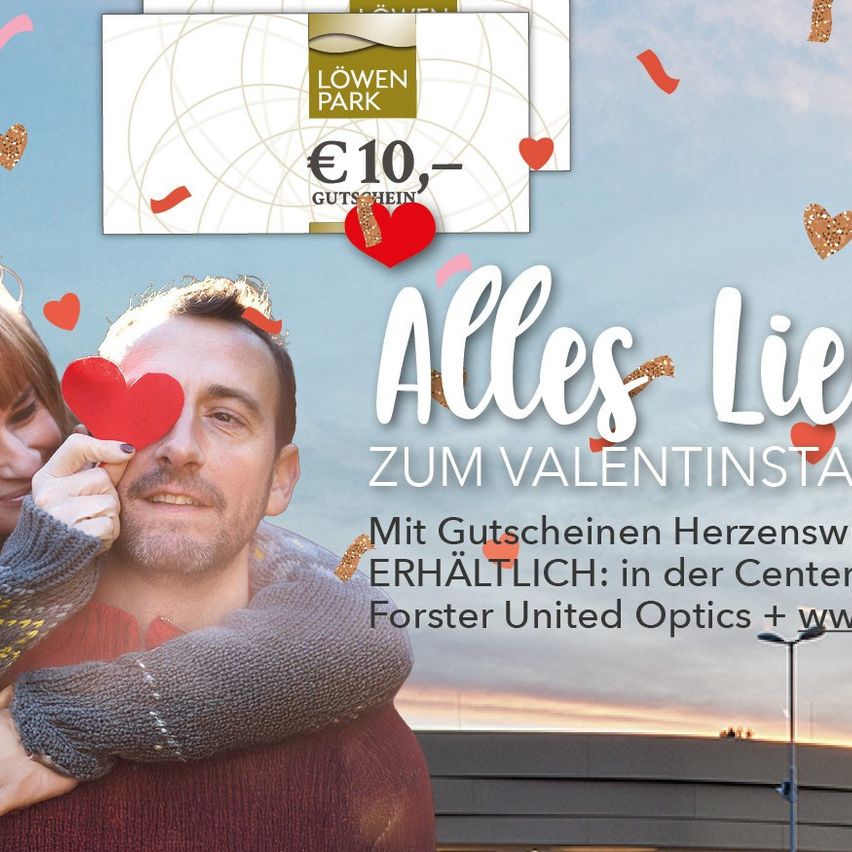 Ein Mann und eine Frau umarmen sich mit einem herzförmigen Filter über den Augen. Der Plakattext lautet Alles Lieb Zum Valentinstag. Es geht um romantische Geschenke. Der Hintergrund ist blau mit Herzen und einem Himmel.