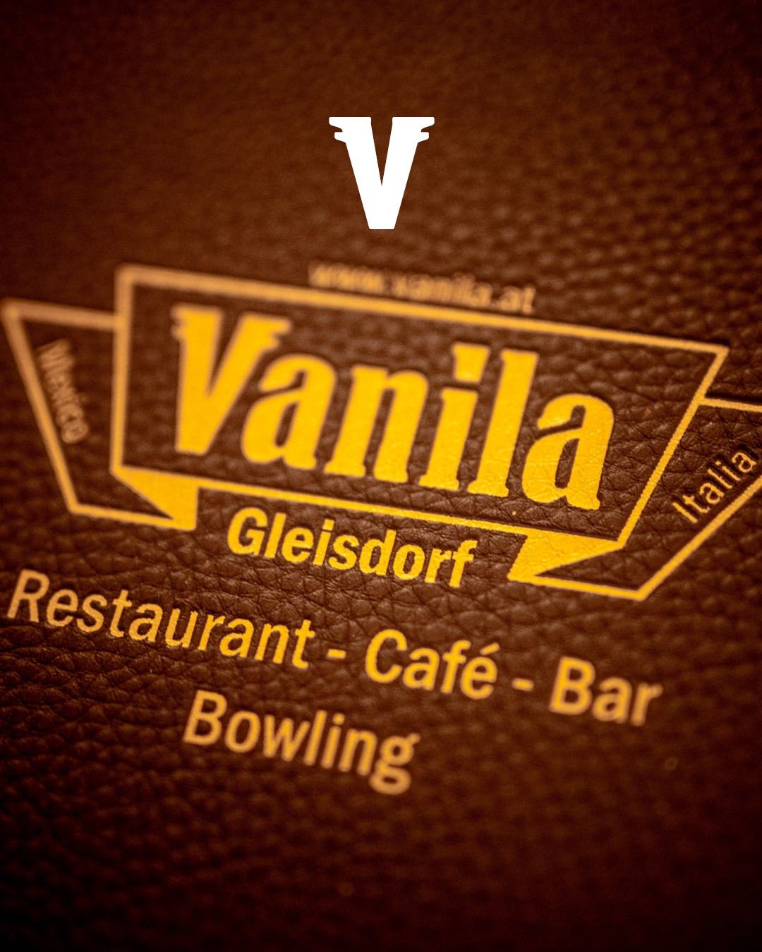 Vanilla Gleisdorf Logo auf einer lederähnlichen Oberfläche mit gelben Akzenten. Beinhaltet die Website www.vanilla.at und den Text 'Restaurant-Café-Bar Bowling'.
