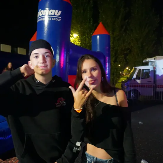 Ein Mann und eine Frau posieren für ein Foto vor einem blauen und roten Aufblasbaren bei Nacht.