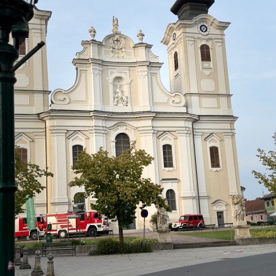 Eine große, kunstvolle Kirche mit zwei Türmen steht prominent, mit zwei Feuerwehrautos davor geparkt.