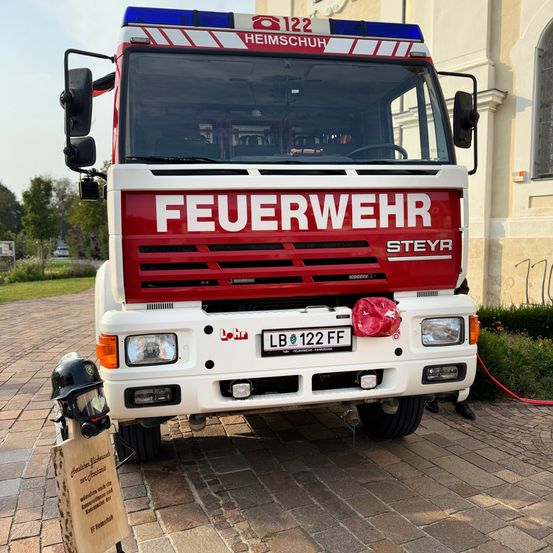 Ein Feuerwehrfahrzeug mit dem Wort Feuerwehr auf der Vorderseite und dem Nummernschild LB 122 FF steht auf einem gepflasterten Weg.