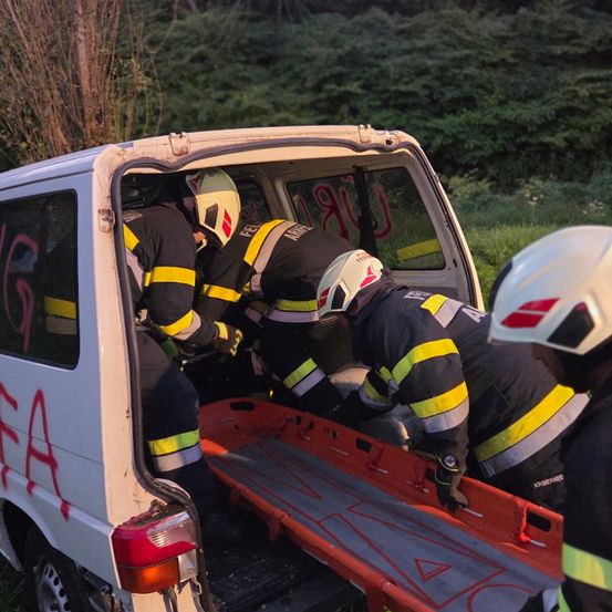 Feuerwehrleute laden eine Trage in den Kofferraum eines weißen Vans, möglicherweise als Reaktion auf einen Notfall.