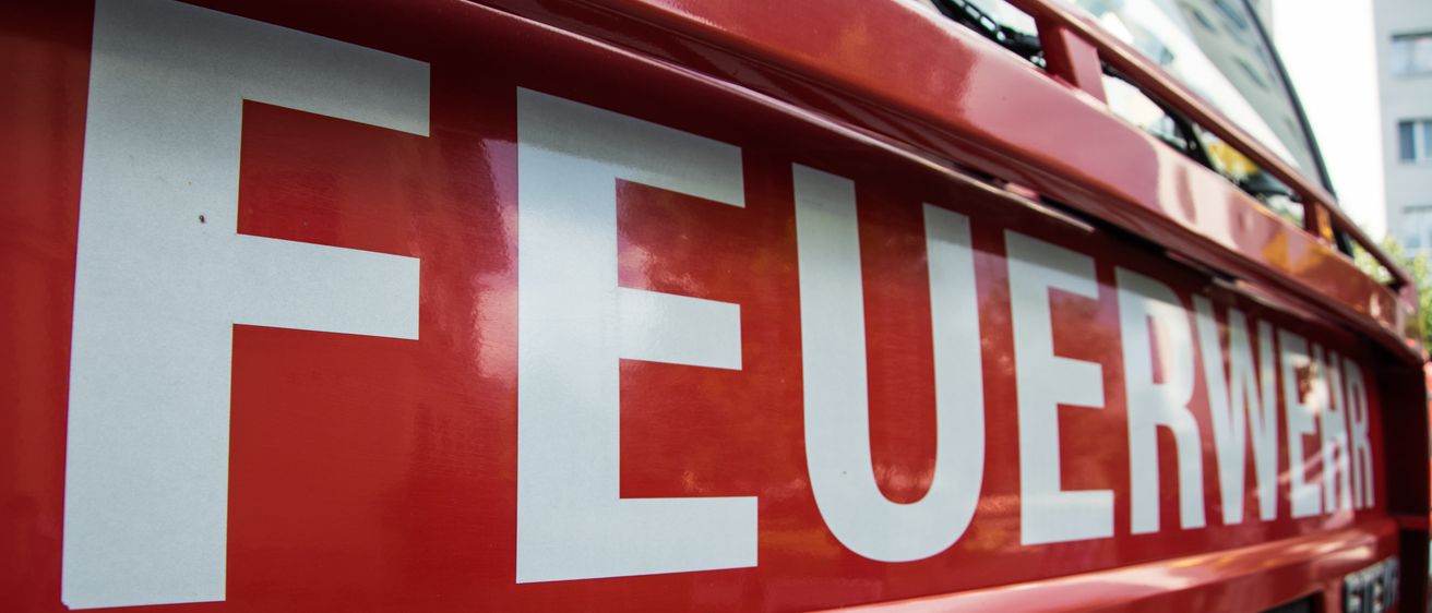 Nahaufnahme des Wortes Feuer auf einem roten Feuerwehrauto mit roter Farbe und weißer Schrift.