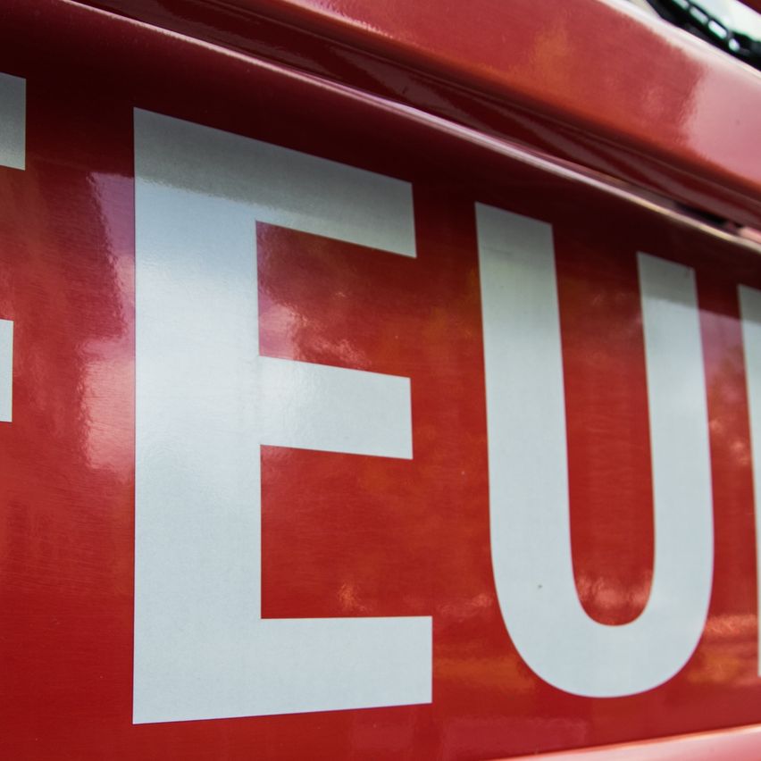Nahaufnahme des Wortes Feuer auf einem roten Feuerwehrauto mit roter Farbe und weißer Schrift.