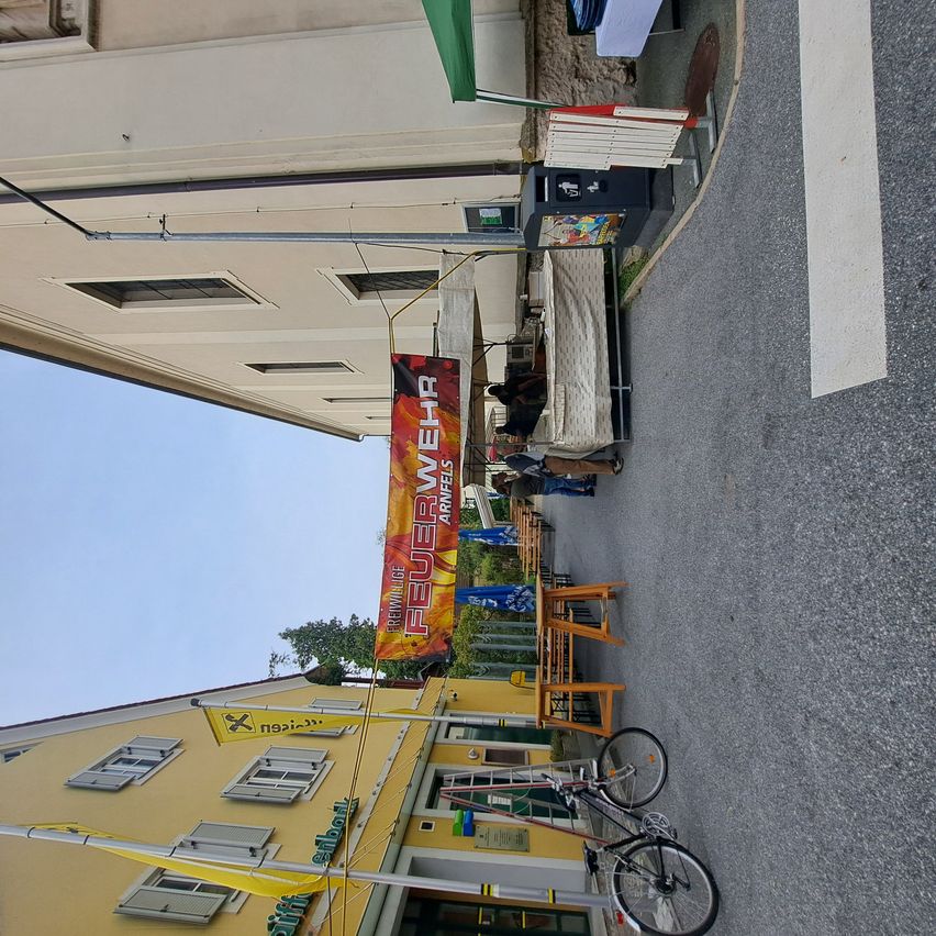 Ein Blick auf eine Straße mit einem Gebäude auf der linken Seite, einem Banner darüber und einem Fahrrad auf der rechten Seite geparkt.