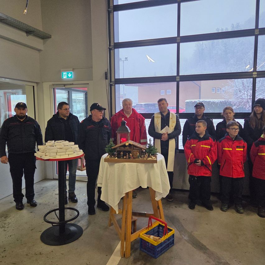 Eine Gruppe von Menschen steht in einer Garage. Eine Weihnachtskrippe steht auf einem Tisch in der Mitte des Raumes.