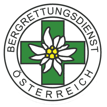 Das Logo des Österreichischen Bergrettungsdienstes zeigt ein grünes Kreuz mit einer weißen Edelweißblume in der Mitte, vor einem weißen kreisförmigen Hintergrund.