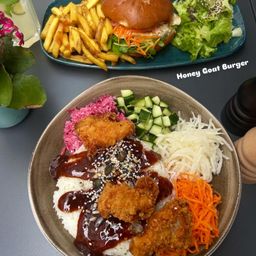 Ein Honey Goat Burger mit Pommes und Salat auf der Seite, und eine Reisschale mit Fleisch, Gemüse und Sauce.