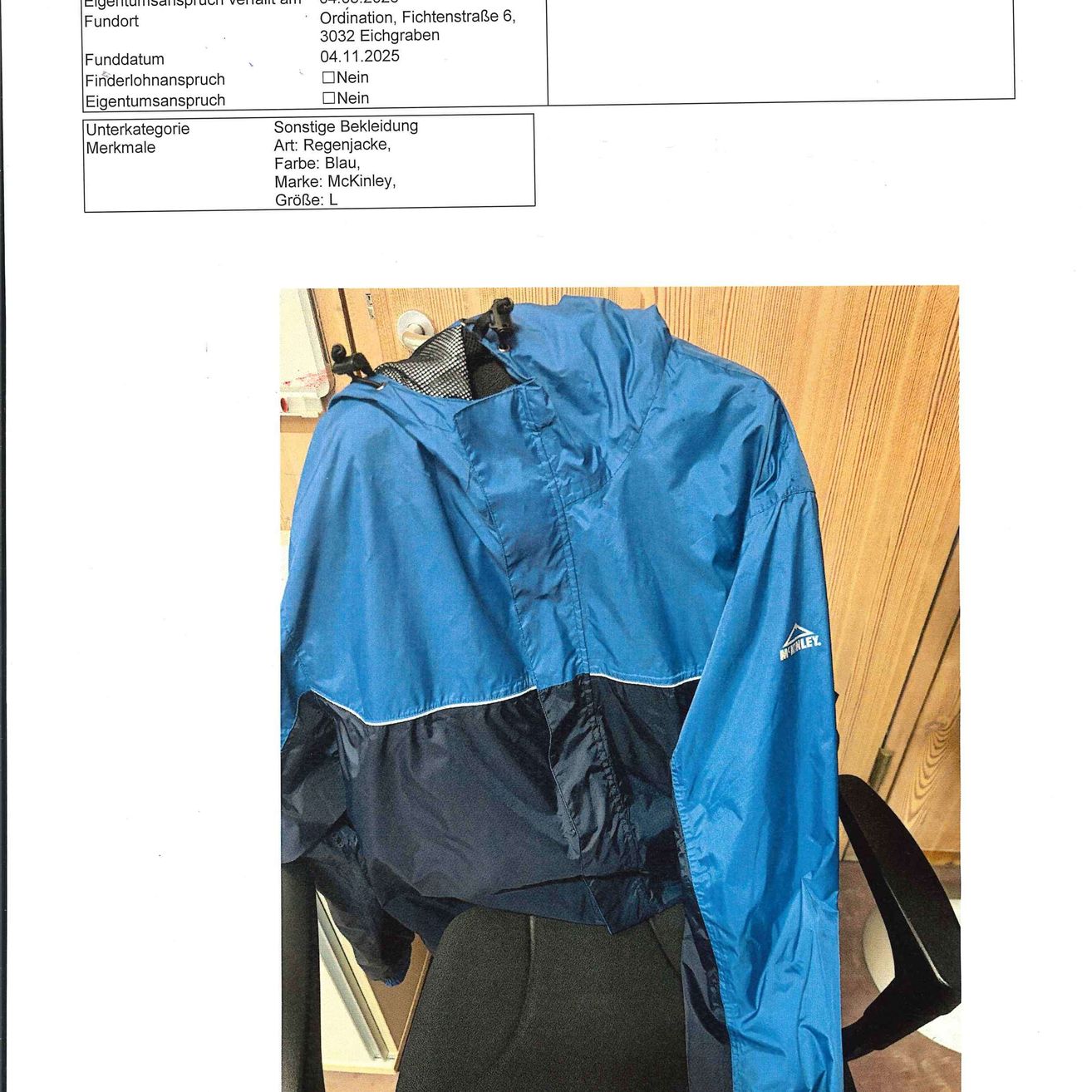 Das Bild zeigt eine blaue Jacke mit schwarzem Innenfutter, die auf einem Stuhl ausgestellt ist. Die Jacke ist mit der Marke McKinley und Größe L beschriftet.