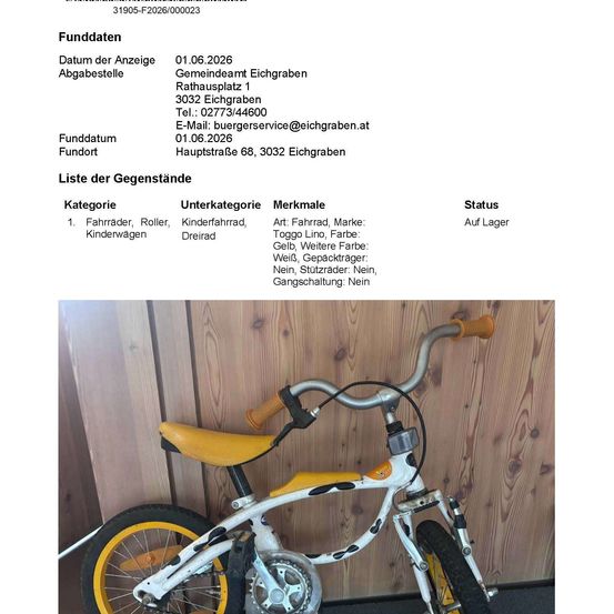 Ein gelbes Fahrrad steht gegen eine Holzwand gelehnt. Das Fahrrad hat einen weißen Rahmen, gelbe Räder und einen gelben Sitz. Die Lenker sind schwarz. Das Fahrrad befindet sich in einem Lagerraum.