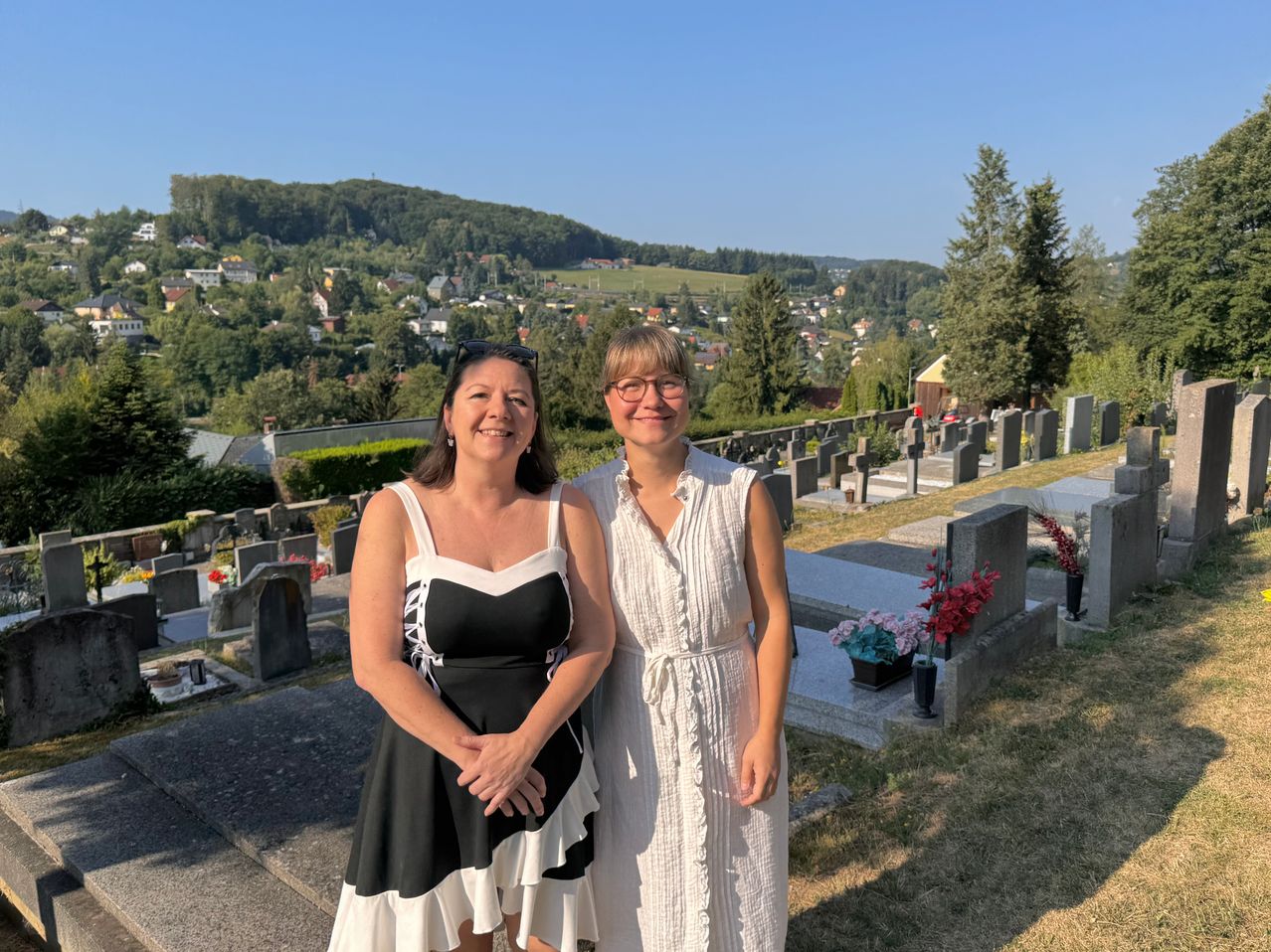 Zwei Frauen vor einem Friedhof mit Blick auf eine Stadt in Oberösterreich