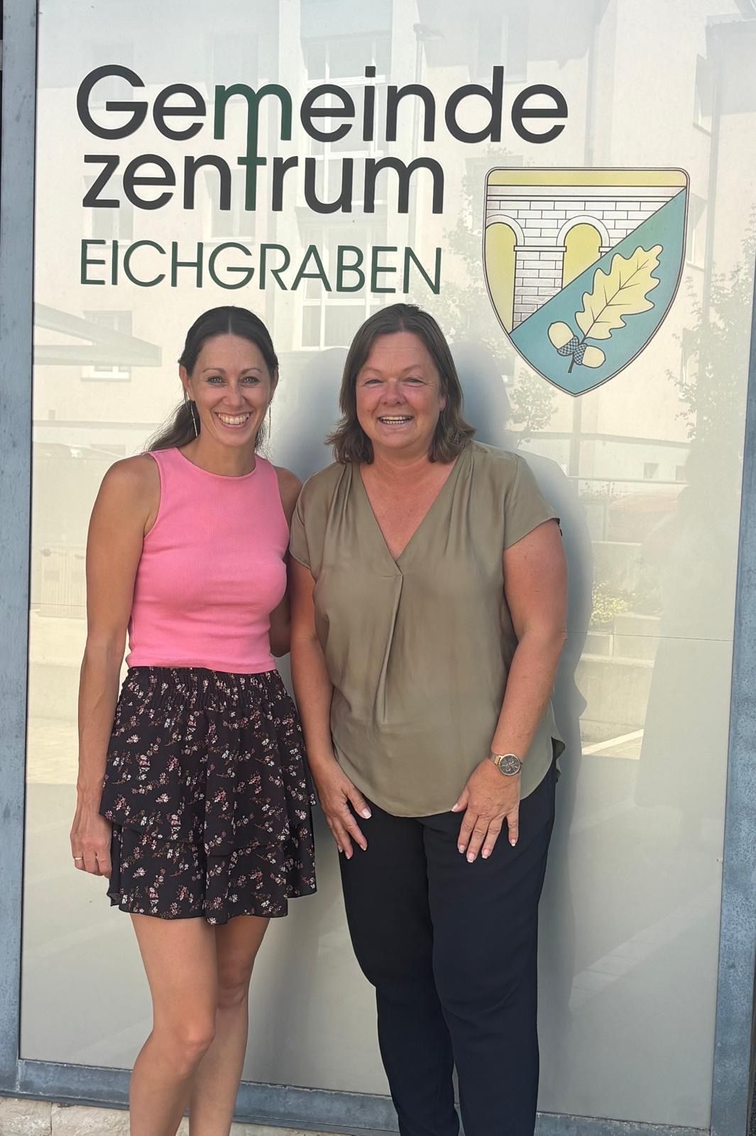 Gemeindezentrum Eichgraben: Zwei Frauen stehen vor dem Gemeindezentrum mit dem Wappen von Eichgraben.