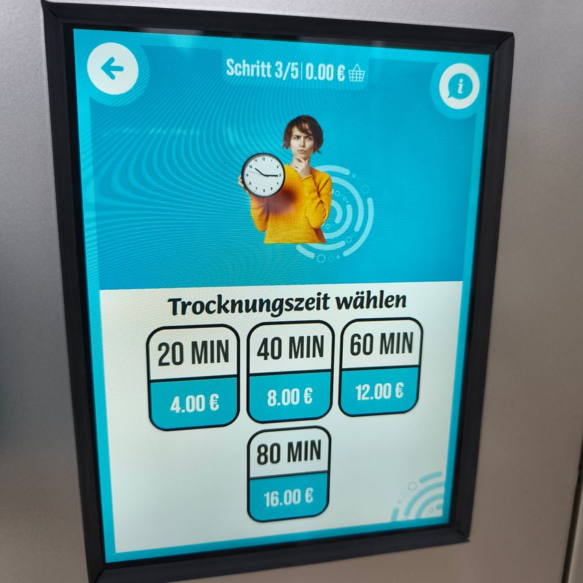 Ein digitales Display zeigt eine Frau, die eine Uhr hält, mit Trocknungszeitoptionen und Preisen darunter aufgeführt.