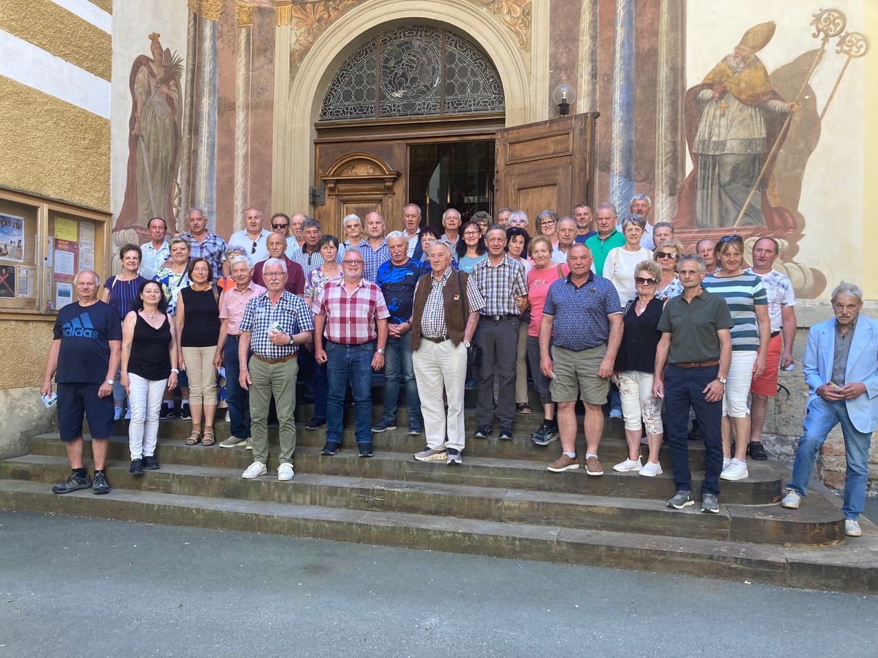 A group of people are posing for a photo in front of a church with a large arch and intricate designs.