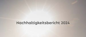 Ein Windpark mit mehreren Windturbinen auf einem weitläufigen Feld, vom Sonnenlicht beschienen. Das Bild zeigt eine Textüberlagerung mit der Aufschrift 'Nachhaltigkeitsbericht 2024'.