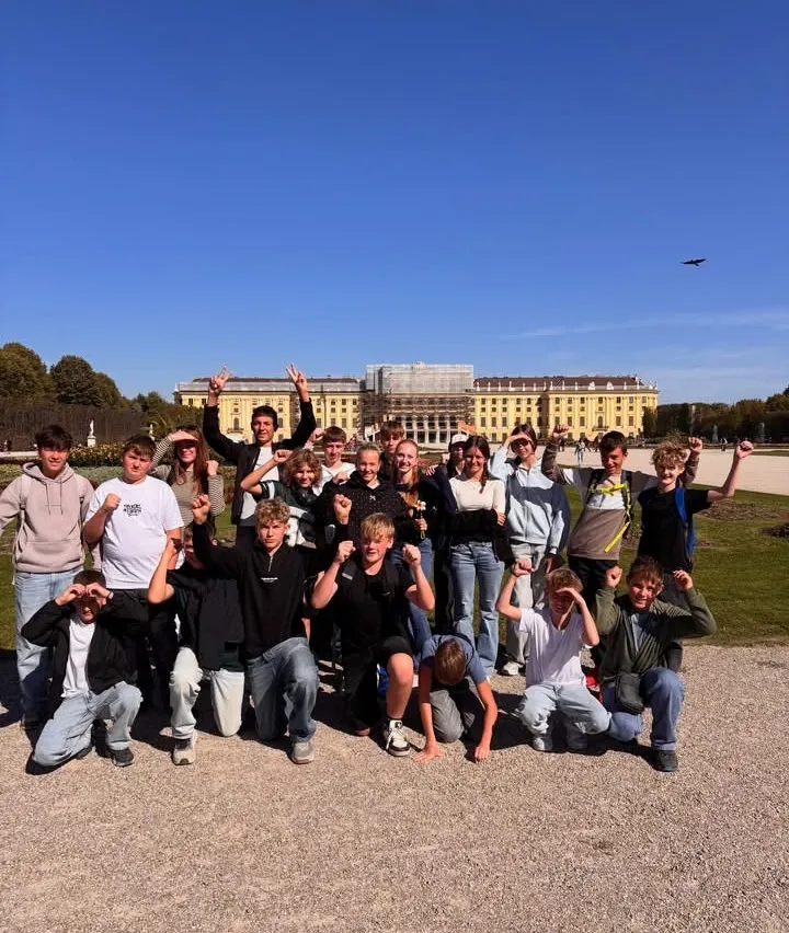 Eine Gruppe junger Menschen posiert für ein Foto vor einem gelben Gebäude.