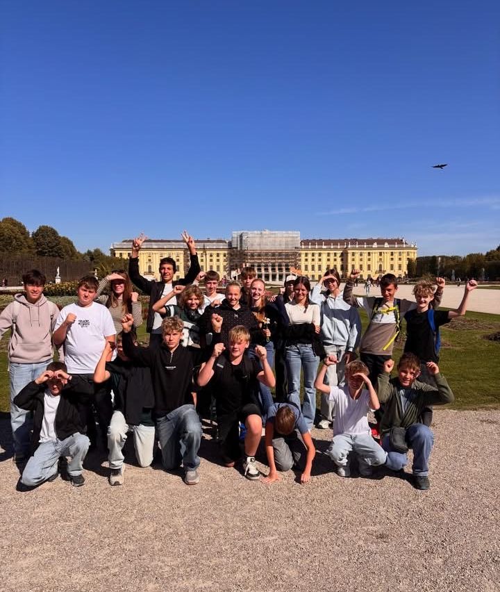 Eine Gruppe junger Menschen posiert für ein Foto vor einem gelben Gebäude.