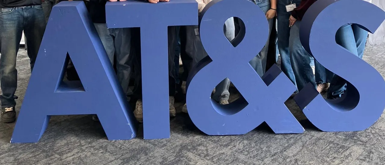 Eine Gruppe von Menschen steht hinter großen blauen Buchstaben, die 'AT&S' bilden.