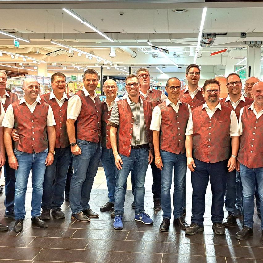 Eine Gruppe von Männern in passenden roten Westen und Brillen posiert für ein Foto in einem Geschäft.