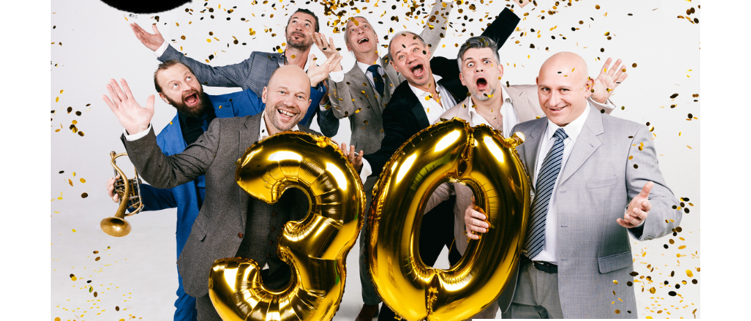 Plakat zur 30-Jahr-Feier von Mnozil Brass mit den Bandmitgliedern in Anzügen, die goldene Luftballons halten, und Konfetti im Hintergrund.