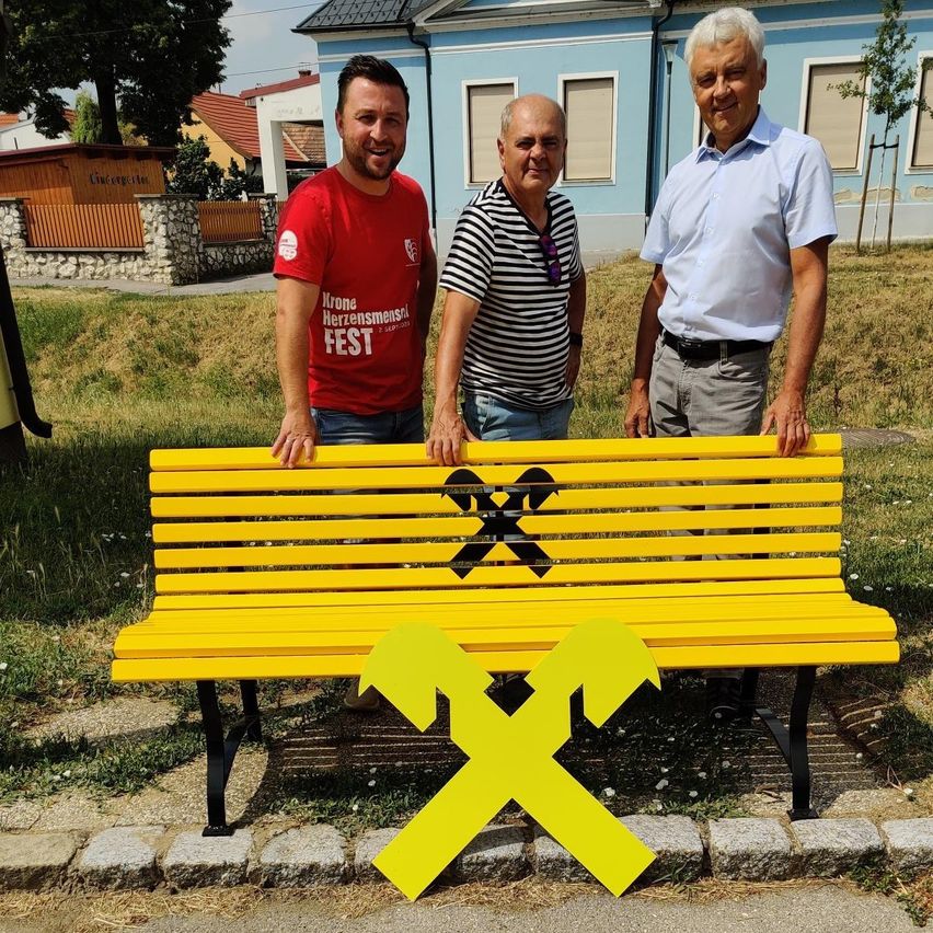  GR Michael Kramer, Obmann des DEV Helmut Kaufmann und Herr Reinhard Riedl (Bankstellenleiter Schrattenberg) stehen vor einer gelben Bank die von der Raika gesponsort worde