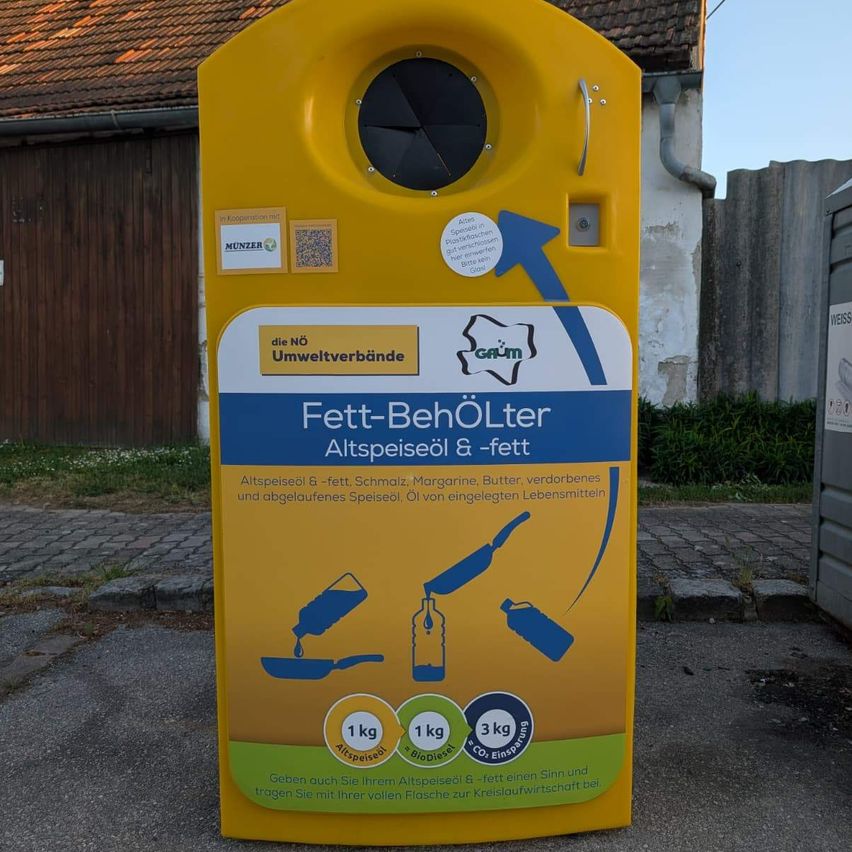 Yellow container for collecting used cooking oil and fat. Instructions and benefits are written in German. It has a capacity of 1kg for oil and 1kg for fat, reducing CO2 emissions by 3kg.