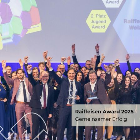 Eine Gruppe von Menschen, meist Männer, feiert mit erhobenen Händen. Sie stehen vor einer Leinwand mit dem 'Raiffeisen Award 2025'. Sie tragen alle formelle Kleidung, und einige halten Auszeichnungen.