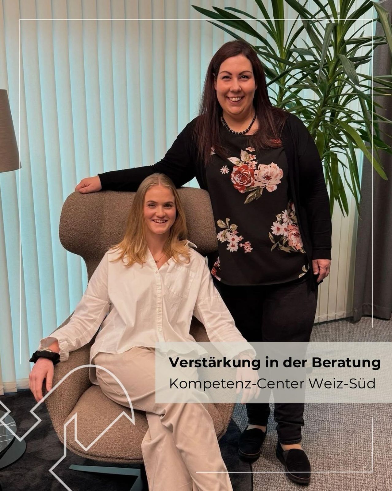 Zwei Frauen in einem Beratungsraum, eine sitzt auf einem Stuhl und die andere steht hinter ihr, beide lächeln. Hinter ihnen eine große Topfpflanze und ein weißer Vorhang. Das Bild hat einen Wasserzeichen mit Text auf Deutsch.