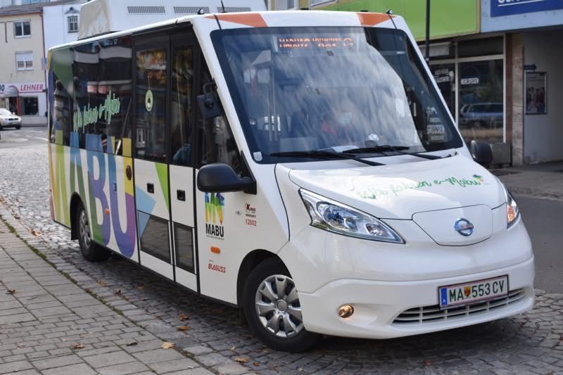 Ein weißer Minibus mit bunten Designs und dem Wort Mabu ist auf einer gepflasterten Straße geparkt.