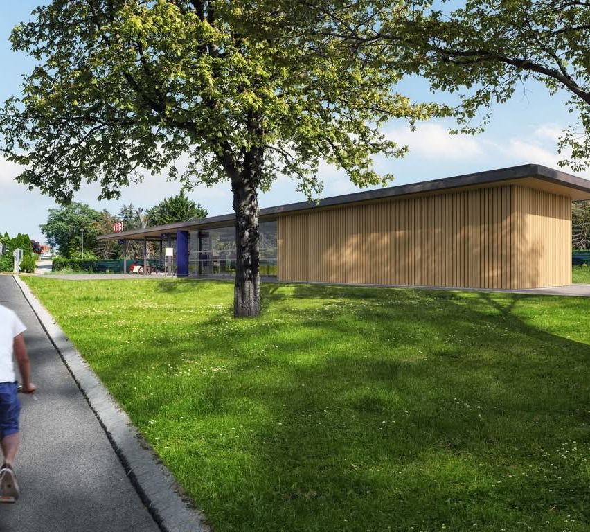 Ein Bild eines modernen Gebäudes mit einem Baum davor, in einem Rasenbereich. Das Gebäude hat ein großes Fenster und einen blauen Pfeiler.