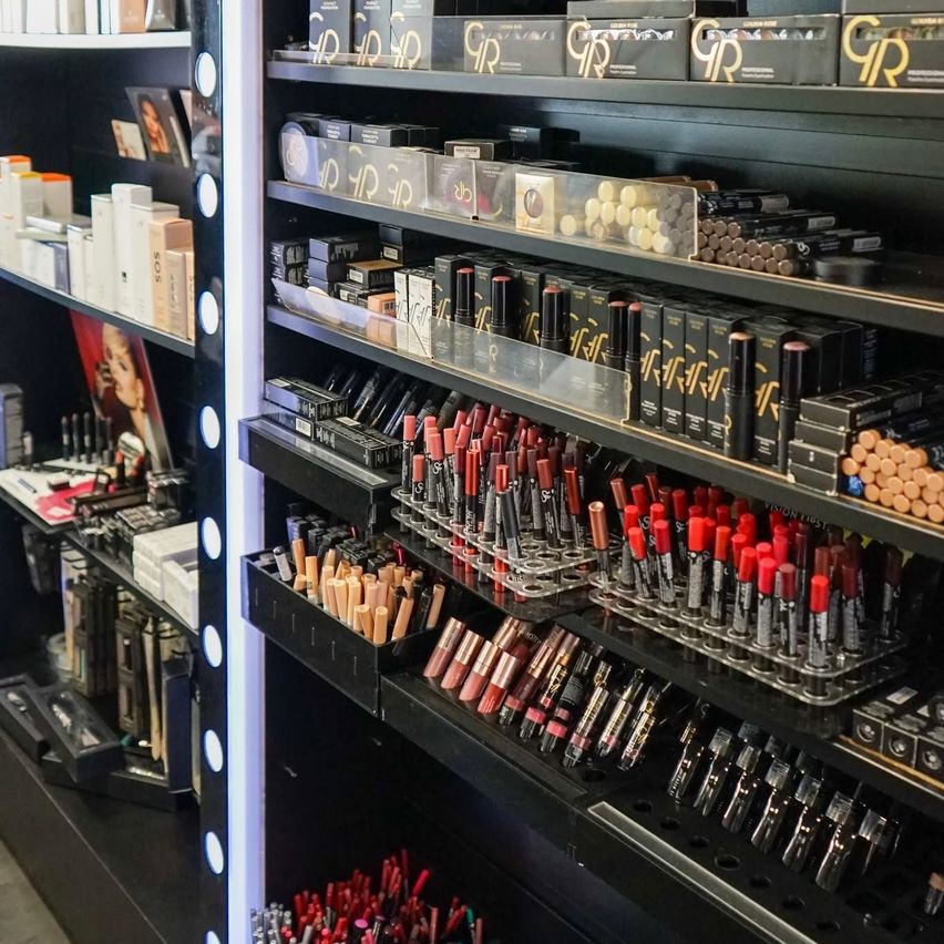 A beauty store filled with makeup products on black shelves, featuring lipsticks, eyeliners, and other cosmetics.