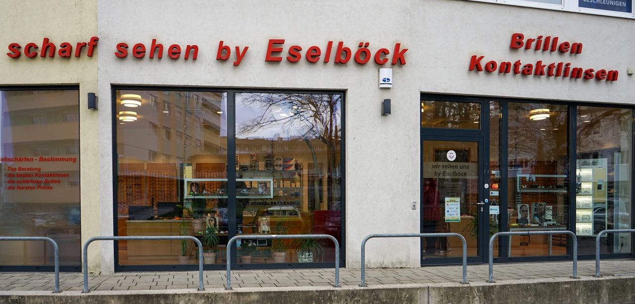 Storefront of a shop named by Eselbock. The display window shows various items with a reflection of a tree and a car.