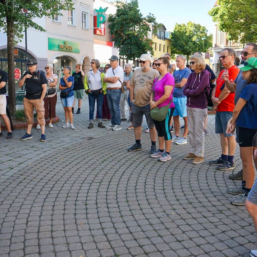 A group of people are standing in a circle outside a building with a sign that says Palmers.