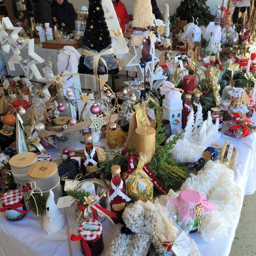 Ein Tisch voller verschiedener Weihnachtsdekorationen und Geschenke, einschließlich Flaschen, Kerzen, Kränze und Ornamente, in einer festlichen Präsentation angeordnet.