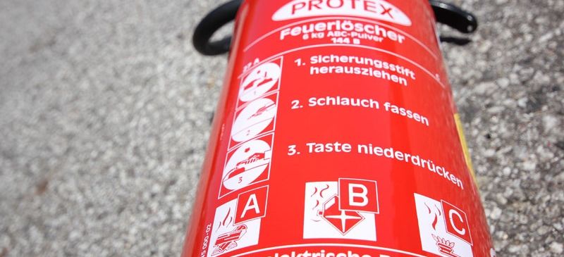 A red Protex fire extinguisher with instructions in German. It's for electrical fires and voltages over 1000 volts. It weighs 6 kg.