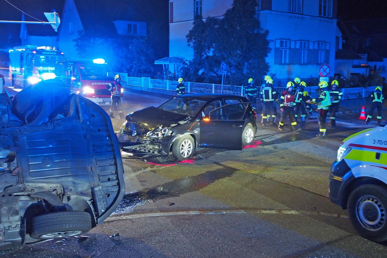 Rettungskräfte reagieren auf einen Autounfall bei Nacht. Ein beschädigtes Auto steht auf der Straße, mit Rettungskräften darum herum.