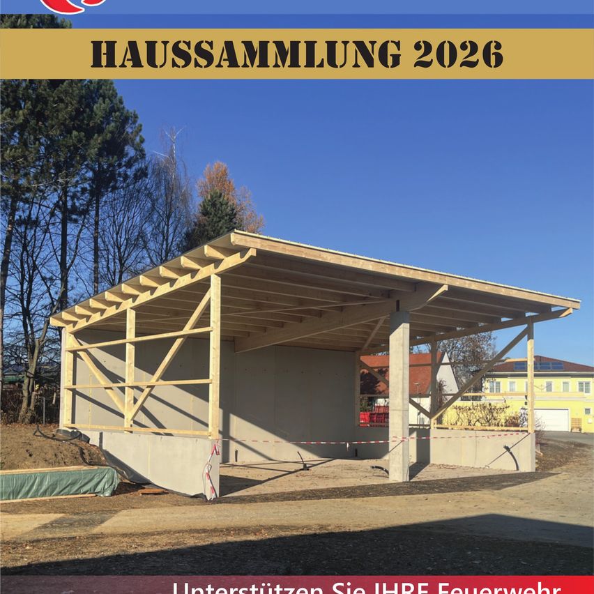 Baustelle für ein Haus im Jahr 2026, mit Holzrahmen, gelbes Gebäude im Hintergrund. Bäume und blauer Himmel sichtbar.