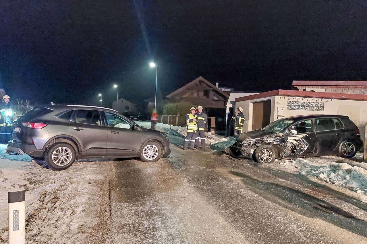 In der Nacht kümmern sich zwei Feuerwehrleute um einen Autounfall, einer in der Nähe eines beschädigten Autos und der andere bei einem geparkten SUV.
