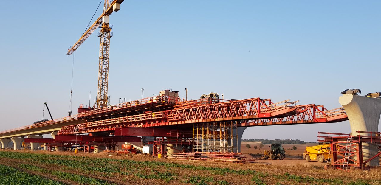Eine große rote Konstruktion einer Brücke im Bau mit einem Kran in der Nähe