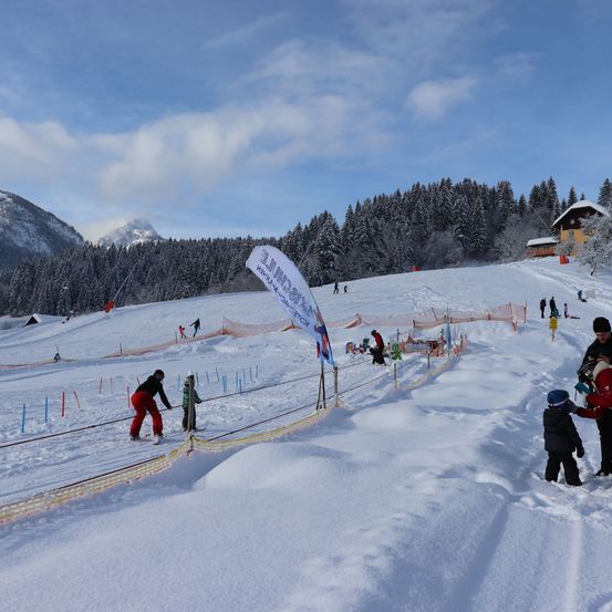 Verschneite Berge und Skipisten mit Skifahrern und Snowboardern im Hintergrund. Die Leute genießen Wintersport.