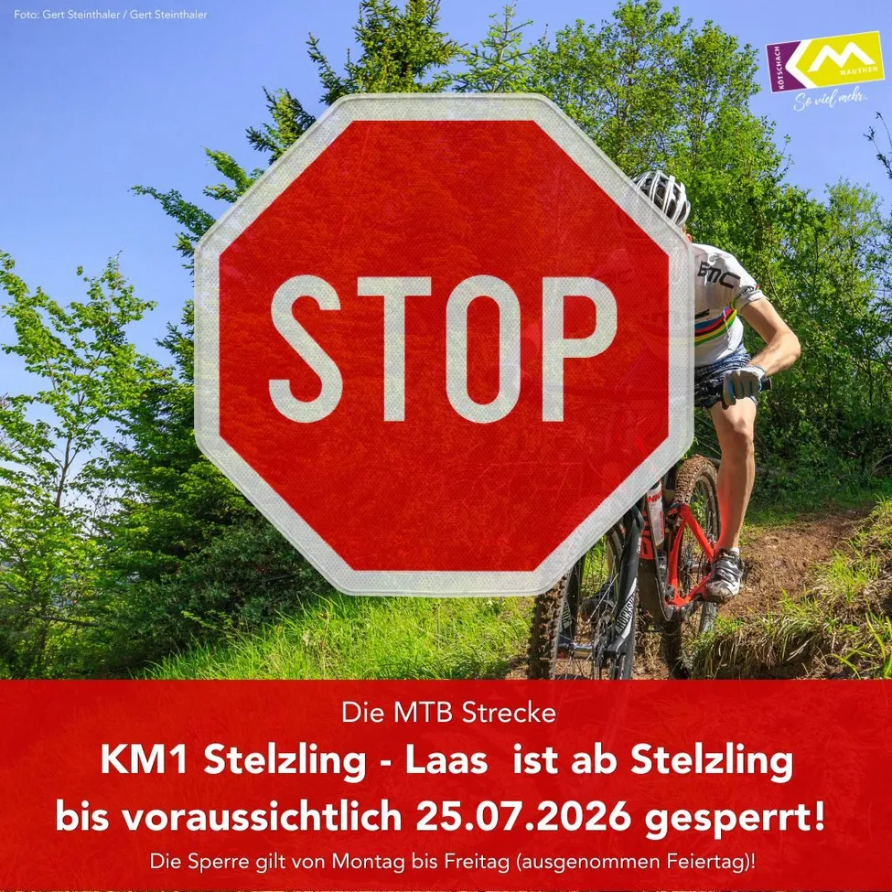Ein Radfahrer fährt auf einem Pfad mit einem roten Stoppschild im Vordergrund. Das Bild enthält eine Nachricht, dass die MTB Strecke KM1 Stelzing bis zum 25.07.2026 gesperrt ist.