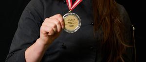 Bild enthält, Gold, Adult, Female, Person, Woman, Gold Medal, Trophy, Coat, Face, Finger