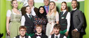 Eine Gruppe von Erwachsenen und Schülern posiert vor einem Hintergrund mit dem Text Tourismus Bad Gleichenberg.