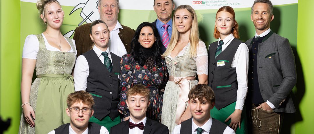 Eine Gruppe von Erwachsenen und Schülern posiert vor einem Hintergrund mit dem Text Tourismus Bad Gleichenberg.