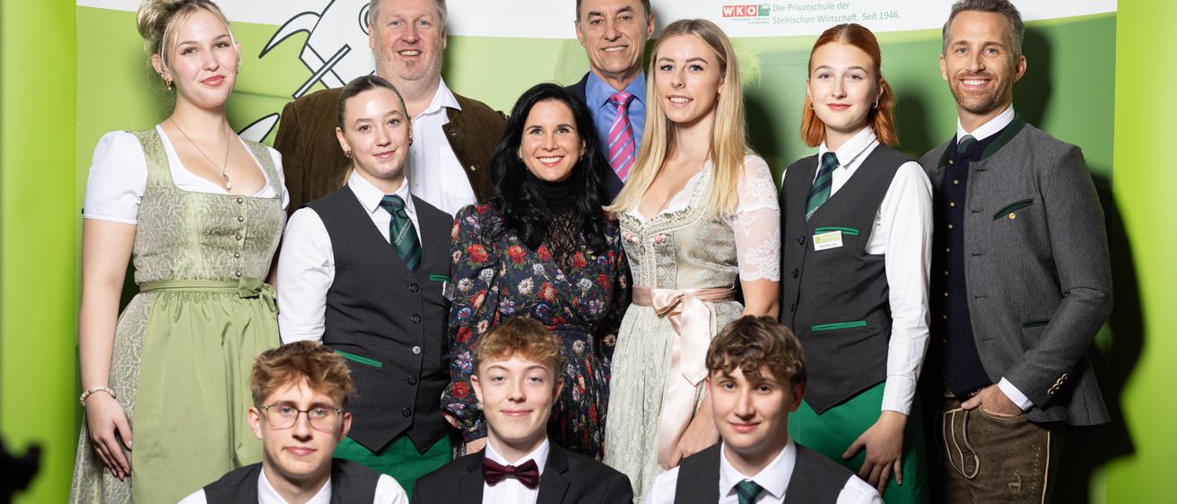 Eine Gruppe von Erwachsenen und Schülern posiert vor einem Hintergrund mit dem Text Tourismus Bad Gleichenberg.