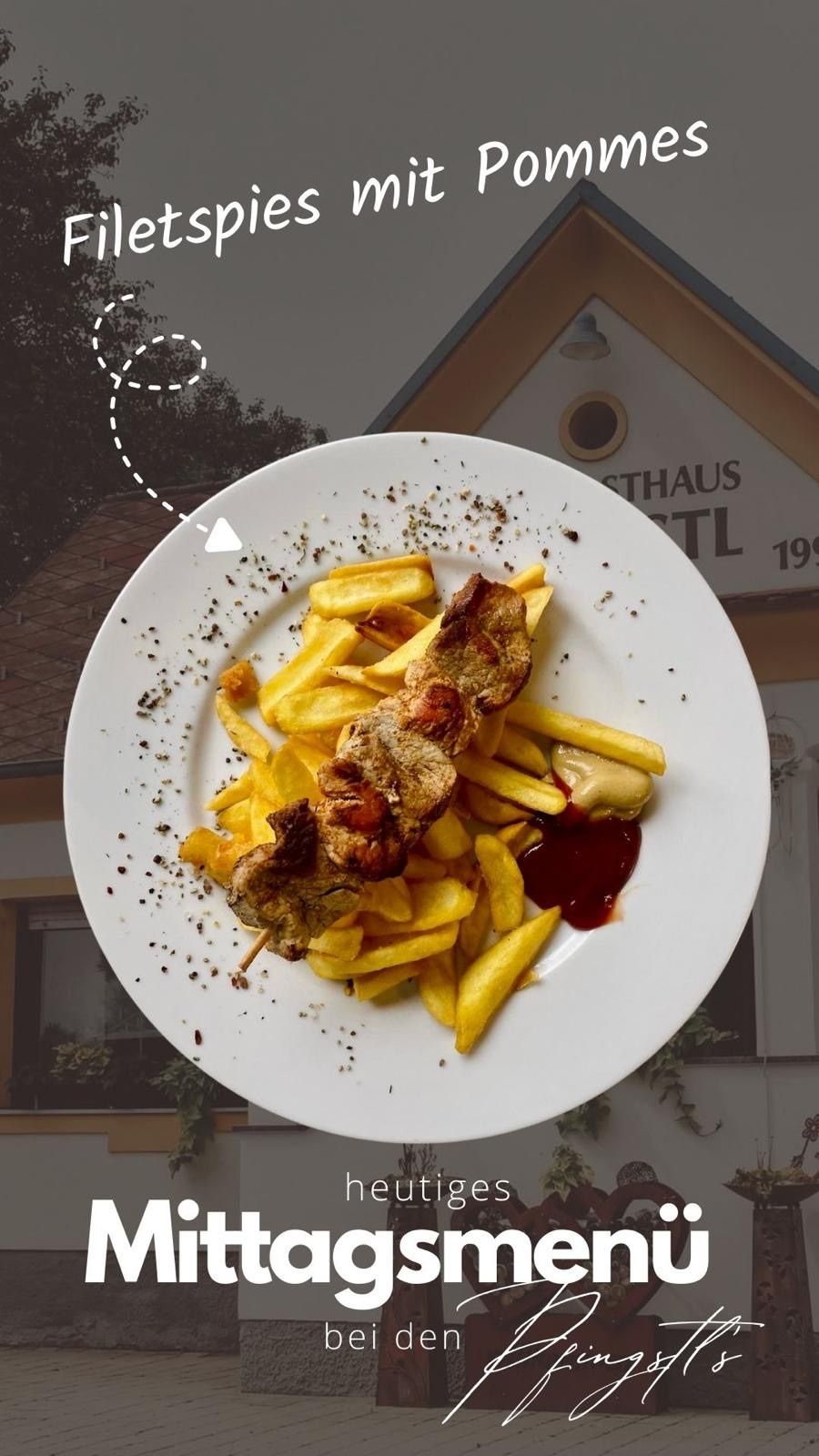 Ein weißer Teller mit gegrilltem Fleisch und Pommes, übergossen mit Sauce, vor einem Gebäude, das Gasthaus TL 199 steht.