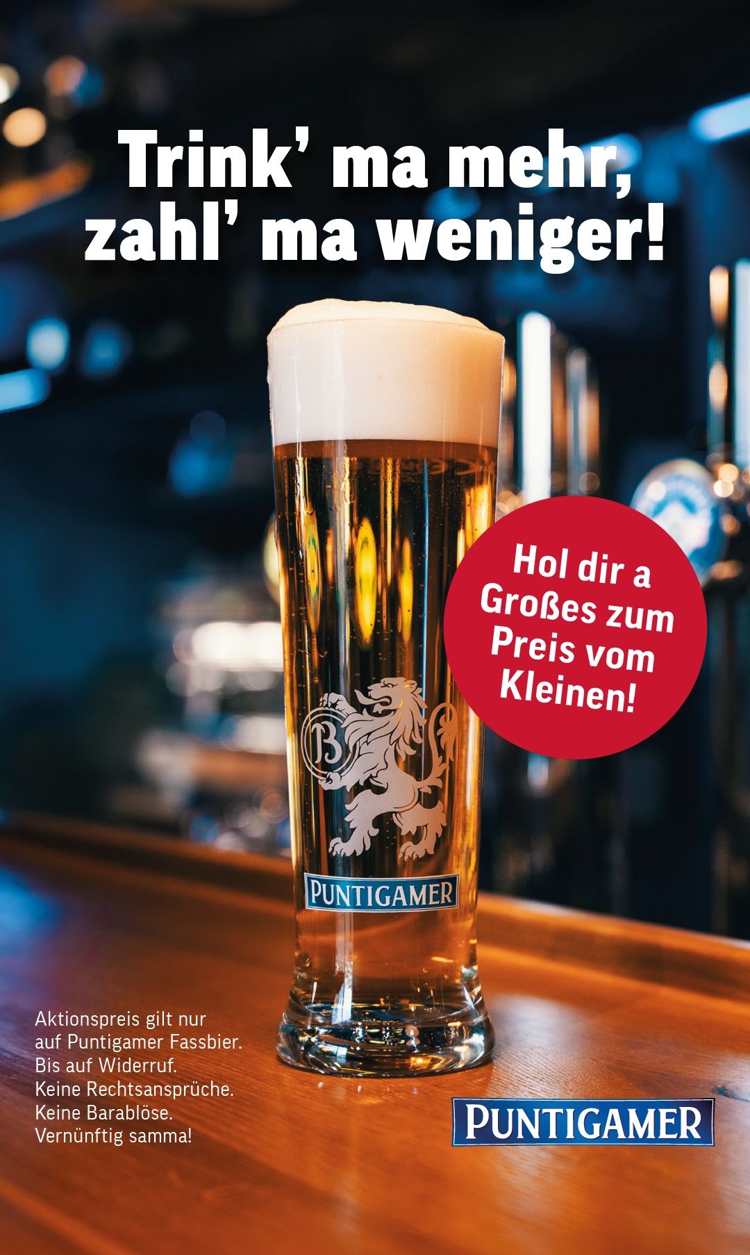 Ein volles Glas Puntigam Bier auf einer Bar mit einem Löwenlogo. Das Schild zeigt 'Hol dir a Grosses zum Preis vom Kleinen!' in Deutsch.